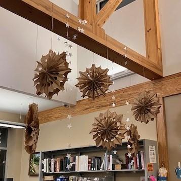 brown paper snowflakes hanging from a wooden ceiling beam