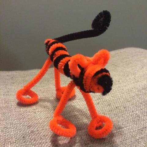 A fuzzy tiger craft made from orange and black pipe cleaners