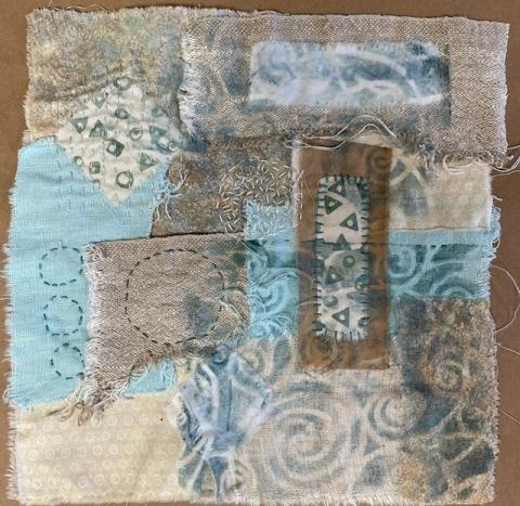 Original Fabric Collage design by Christy Ammerman, small scraps of blue and brown fabric and patterned fabric are layered and hand stitched together, forming a square piece.