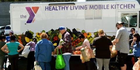 People in front of the YMCA mobile market truck, choosing food from bins. 