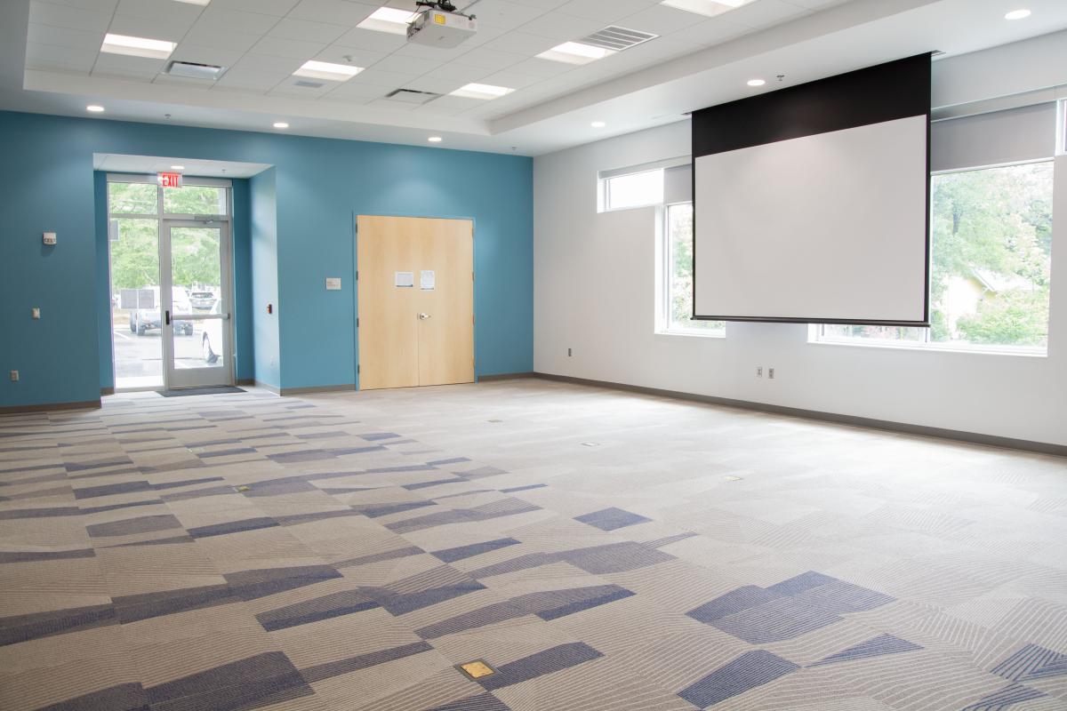 carpeted empty room with projector screen and door leading outside