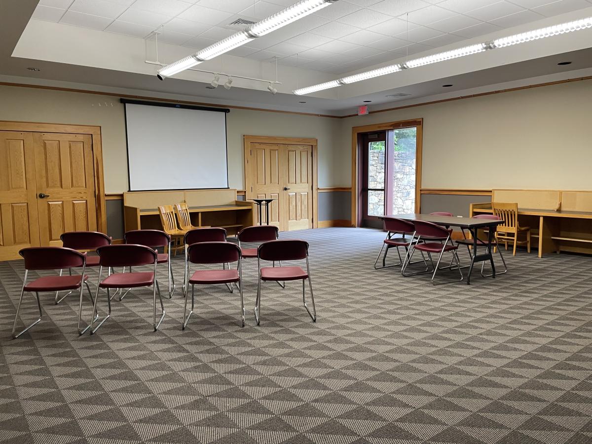 carpeted room with chairs, tables, projector screen