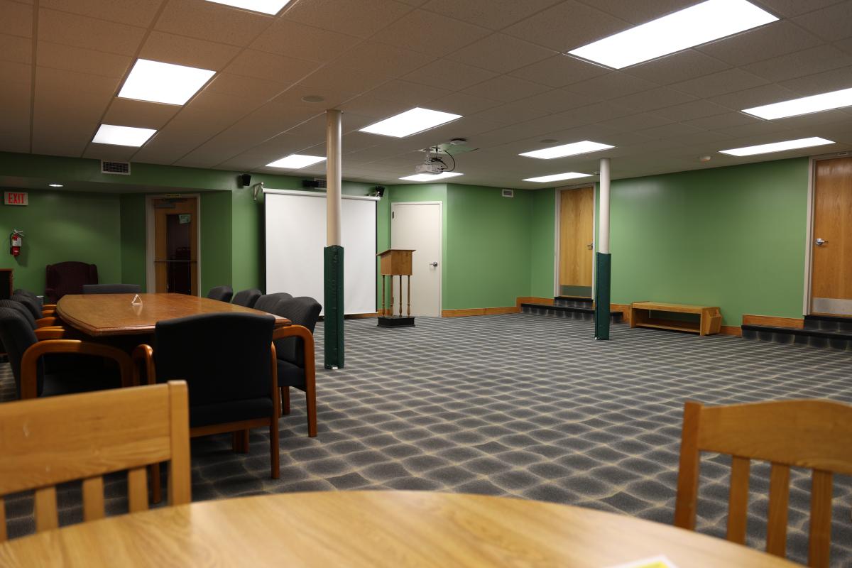 carpeted room with wooden tables and wooden chairs with fabric upholstery