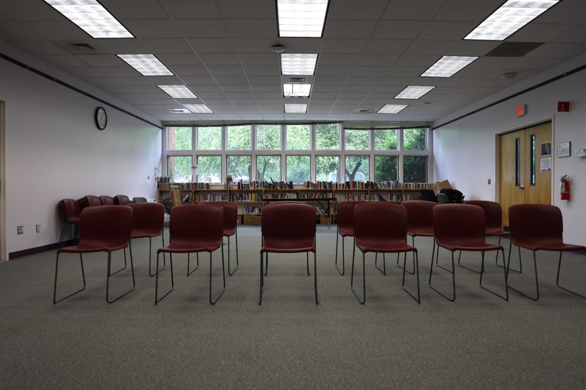 carpeted room with windows on the whole back wall and two rows of plastic chairs with metal frame