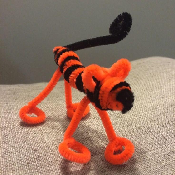 A fuzzy tiger craft made from orange and black pipe cleaners